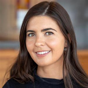 Laura has long brown hair and is smiling at the camera