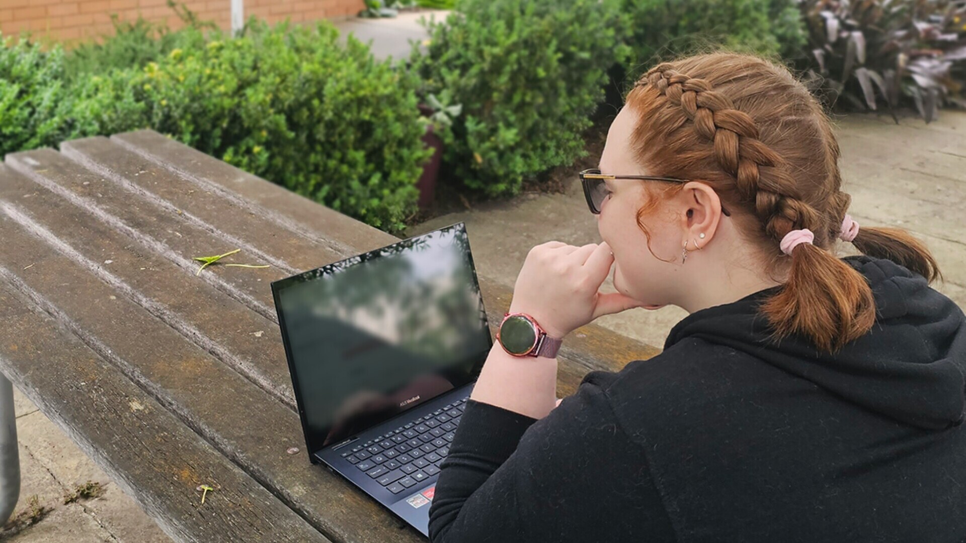 Young woman working on her laptop outside