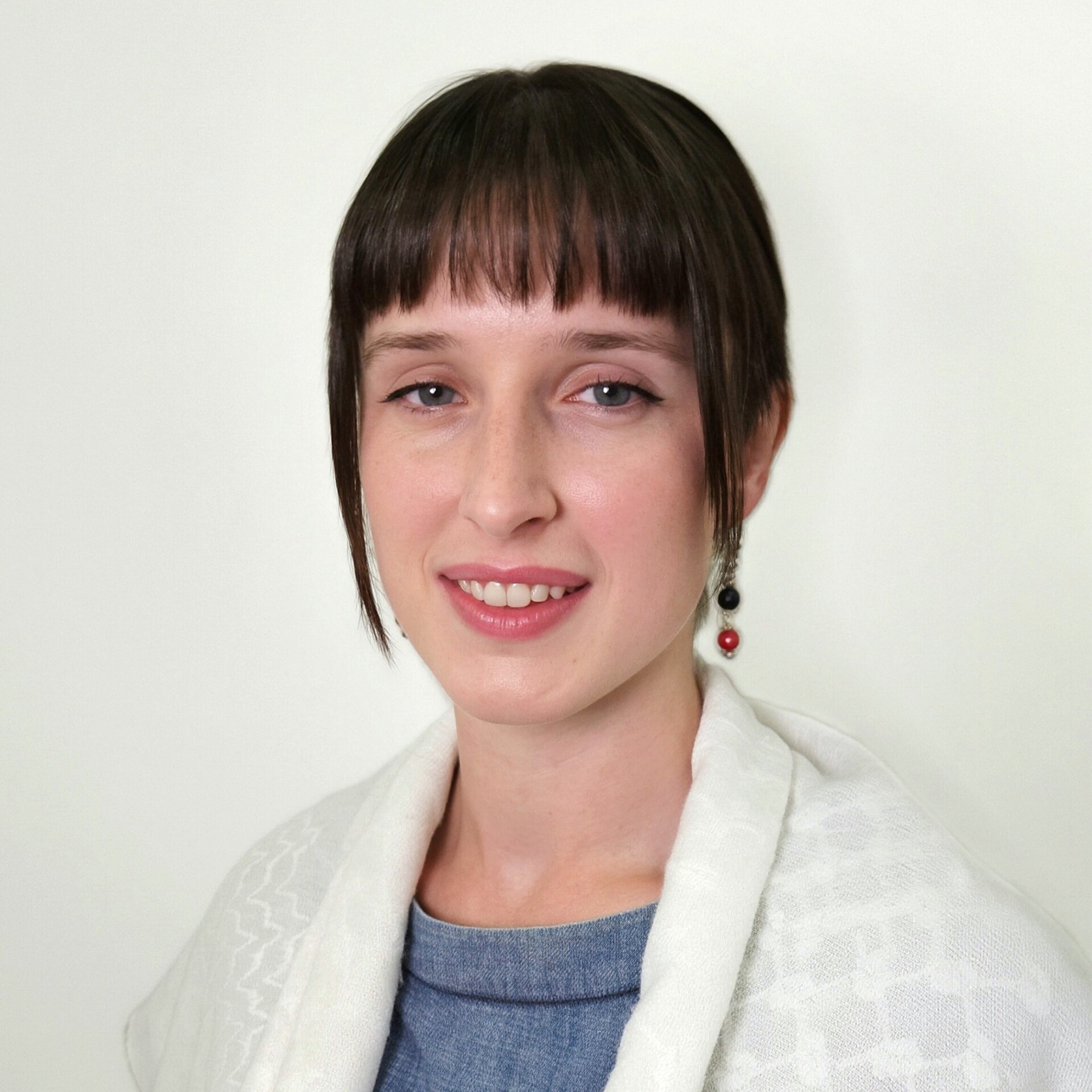 Anna smiles, she has dark hair and is wearing a light shawl over her shoulders.