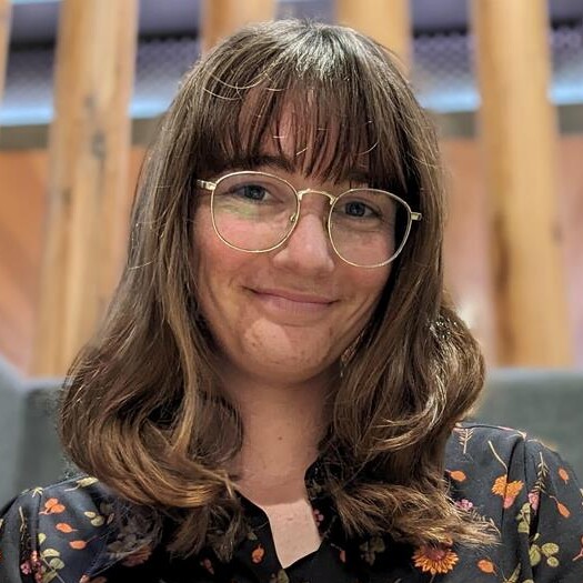 Annaliese has shoulder length brown hair is wearing glasses and a colourful shirt
